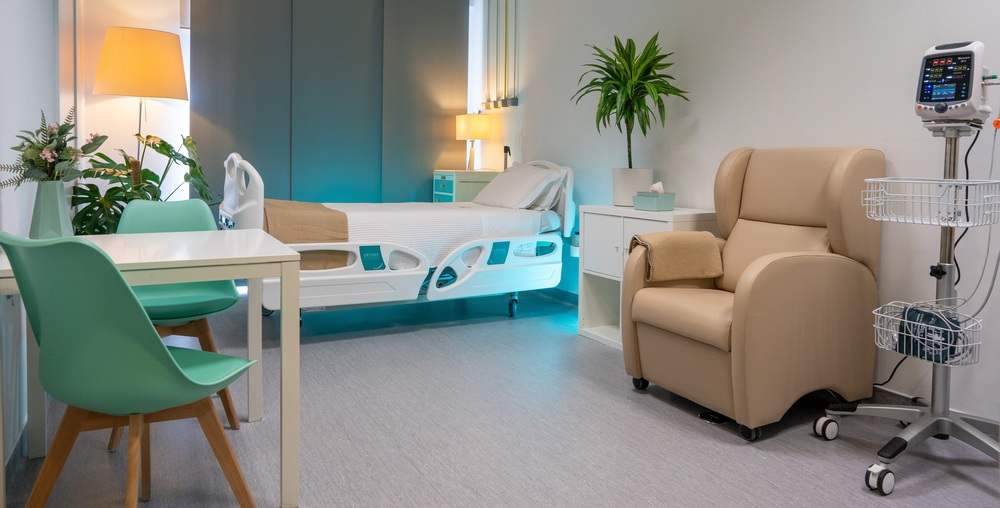 A room with a bed, a reclining armchair and natural light.