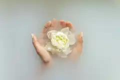 Hands cupping a white flower on water
