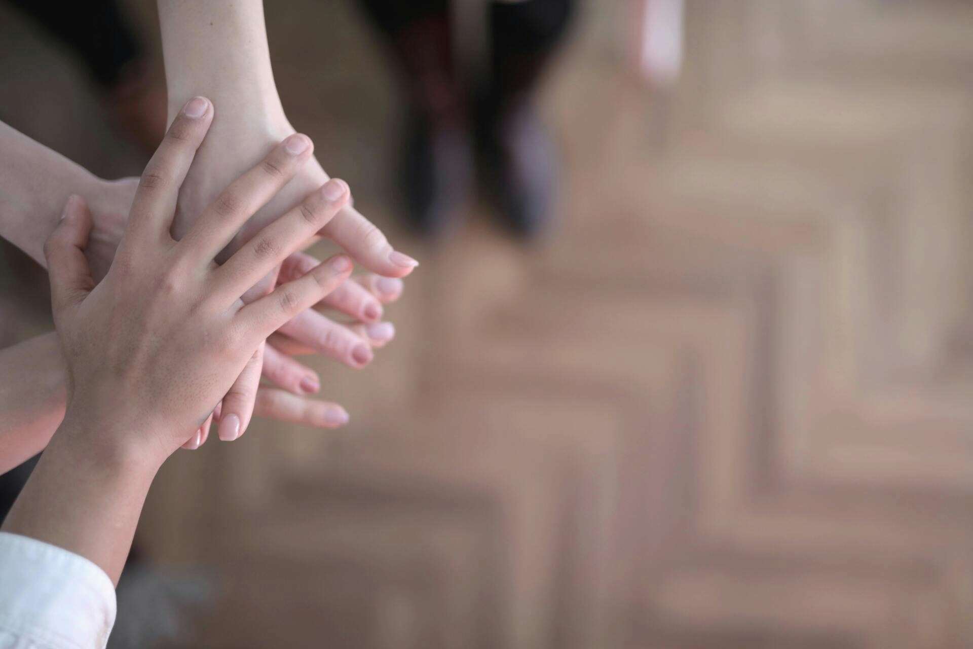 Hands placed together in a gesture of support and sharing